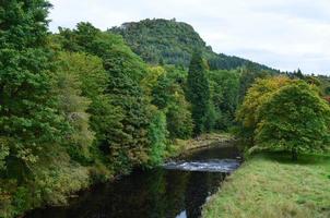 lindamente exuberante paisagem verde com um rio na Escócia foto