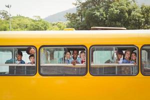 alunos bonitos sorrindo para a câmera no ônibus escolar