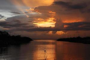 céu dramático colorido com nuvens ao pôr do sol. pôr do sol no lago foto