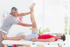 fisioterapeuta fazendo perna esticando para seu paciente foto