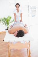 paciente relaxante na mesa de massagem com fisioterapeuta por trás foto