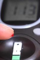 closeup de dedo com medidor de sangue e glicose
