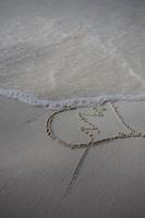 corações desenhados na areia de uma praia foto