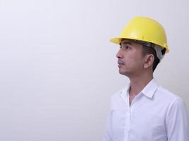 engenheiro com as mãos cruzadas usando capacete amarelo sobre fundo branco foto