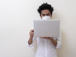 homem de negócios com máscara facial médica trabalha no laptop em casa