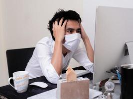 jovem rapaz asiático usando máscara facial trabalhando no computador portátil durante a pandemia de coronavírus foto