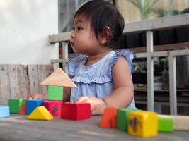 menina asiática brincando com blocos de madeira no chão foto