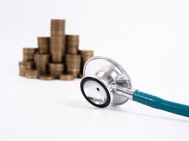 estetoscópio na pilha de moedas, sobre fundo branco. dinheiro para cuidados de saúde, ajuda financeira, conceito foto