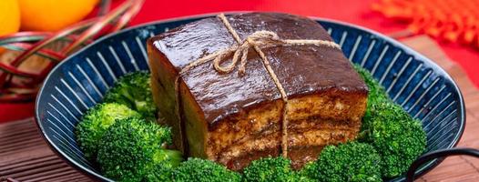 dong po rou dongpo carne de porco em uma bela placa azul com vegetais de brócolis verde, comida tradicional festiva para refeição de cozinha de ano novo chinês, close-up. foto