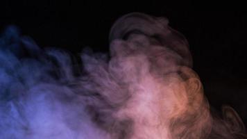 imagem conceitual de fumaça multicolorida isolada em fundo preto escuro e mesa de madeira. foto