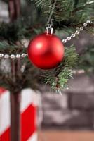 árvore de natal decorada com lindos presentes vermelhos e brancos embrulhados em casa com parede de tijolos pretos, conceito de design festivo, close-up. foto