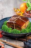 dong po rou dongpo carne de porco em uma bela placa azul com vegetais de brócolis verde, comida tradicional festiva para refeição de cozinha de ano novo chinês, close-up. foto