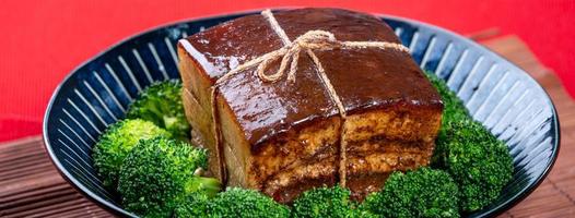 dong po rou dongpo carne de porco em uma bela placa azul com vegetais de brócolis verde, comida tradicional festiva para refeição de cozinha de ano novo chinês, close-up. foto