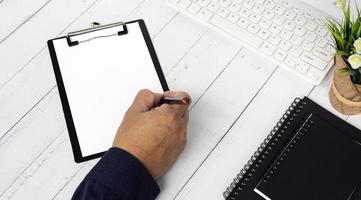 mãos de empresário com caneta escrevendo caderno na mesa de escritório com. foto