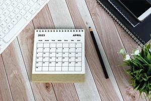 calendário de mesa de abril de 2023 branco na mesa de madeira. diretamente acima. postura plana. foto