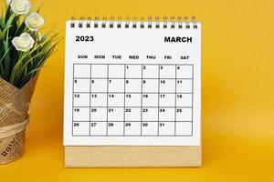 calendário de março de 2023 branco com vaso de plantas em fundo amarelo. foto