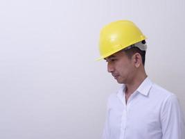 engenheiro com as mãos cruzadas usando capacete amarelo sobre fundo branco foto