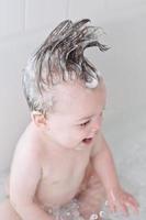 menino com shampoo up-do espirrando na banheira foto
