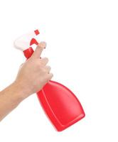 mão segurando o frasco de spray de plástico vermelho. foto