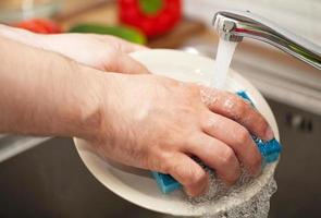 mãos de homem lavando pratos foto