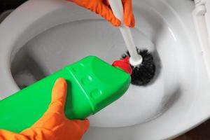 mão com luvas de limpeza de vaso sanitário usando escova foto
