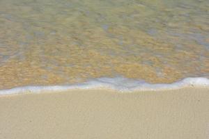 água lambendo suavemente a costa com pequenas bolhas foto