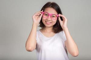 retrato de menina adolescente asiática sorrindo e usando óculos cor de rosa