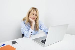 empresária jovem entediada, usando o laptop na mesa no escritório