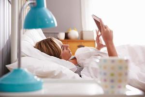 mulher na cama, olhando para tablet digital foto