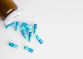 cápsulas de medicamento azul e frasco foto