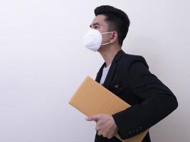 funcionário do serviço de entrega feliz com máscara facial médica carrega caixa de papelão na mão foto