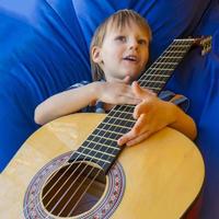 garotinho toca violão e canta na varanda foto