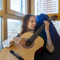 jovem tocando violão clássico na varanda foto