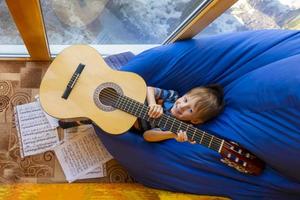 garotinho toca violão e canta na varanda foto