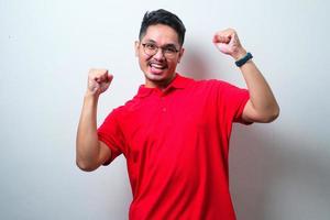 jovem bonito vestindo camisa casual e óculos muito feliz e animado fazendo gesto de vencedor com os braços levantados, sorrindo e gritando para o sucesso. conceito de celebração foto