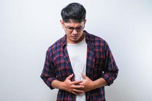 jovem asiático com dor de estômago ou dor abdominal problema de saúde desconforto diarreia isolado foto
