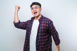 gesto de vencedor de mandoing jovem asiático com os braços levantados, sorrindo e gritando para o sucesso. conceito de celebração foto