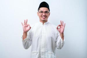 homem muçulmano asiático aprova fazendo gesto positivo com a mão, polegares para cima sorrindo e feliz pelo sucesso. gesto do vencedor. foto