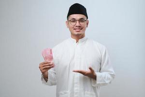 homem muçulmano asiático sorrindo feliz enquanto segura papel-moeda foto