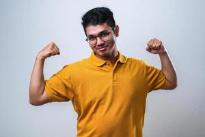 jovem asiático bonito mostrando os músculos dos braços sorrindo orgulhoso. conceito de aptidão. foto