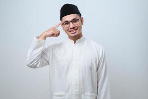 sorrindo jovem muçulmano asiático apontando para a cabeça com o dedo. foto