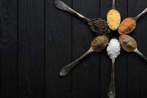 coloridas várias ervas e especiarias para cozinhar em fundo rústico de madeira escura foto