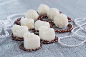 chocolates em forma de coração com balas de coco em flocos de miçangas foto