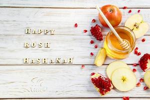 feliz Rosh Hashaná. inscrição em fundo de madeira. símbolos tradicionais de celebração. maçãs, romãs e mel. foto