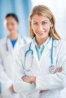feliz médico feminino em pé braços cruzados na clínica