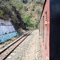 trem de brinquedo movendo-se nas encostas das montanhas, bela vista, uma montanha lateral, um vale lateral movendo-se na ferrovia para a colina, entre a floresta natural verde. trem de brinquedo de kalka para shimla na índia, trem indiano foto