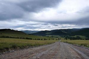 fita da estrada entre as encostas das montanhas nas extensões de altai em um dia de verão foto