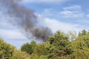 fumaça preta da queima de árvores e edifícios da floresta foto