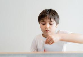 criança usando tesoura cortando papel branco, estudante fazendo arte e artesanato para sua lição de casa, criança aprendendo a usar a tesoura cortando o papel, crianças aprendem e brincam em casa, conceito de escola em casa foto