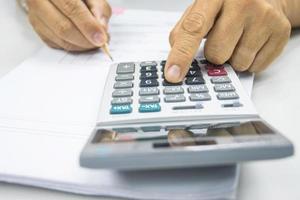 mão do homem usa uma calculadora para calcular receitas e despesas nos conceitos de escritório foto